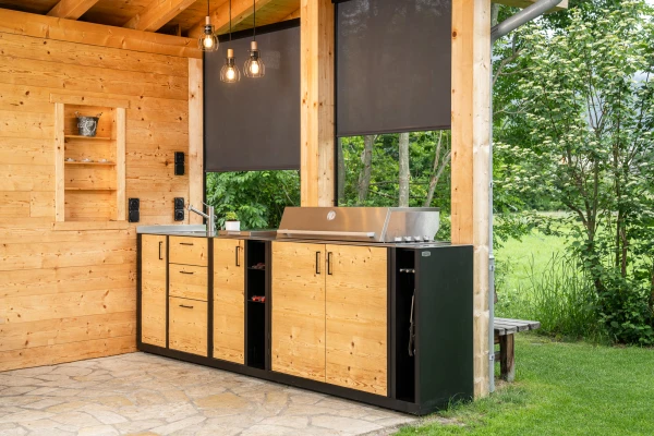 Massgeschneiderte Outdoorküche mit Holzfront und Grillstation in Sils im Domleschg.