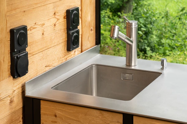 Edelstahl-Arbeitsfläche mit integriertem Spülbereich und Grillstation.